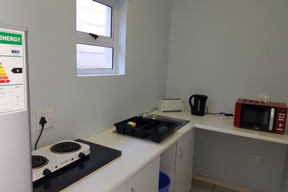 A compact kitchenette featuring white cabinetry, a stainless steel sink, and a portable electric hob, suitable for basic food preparation.