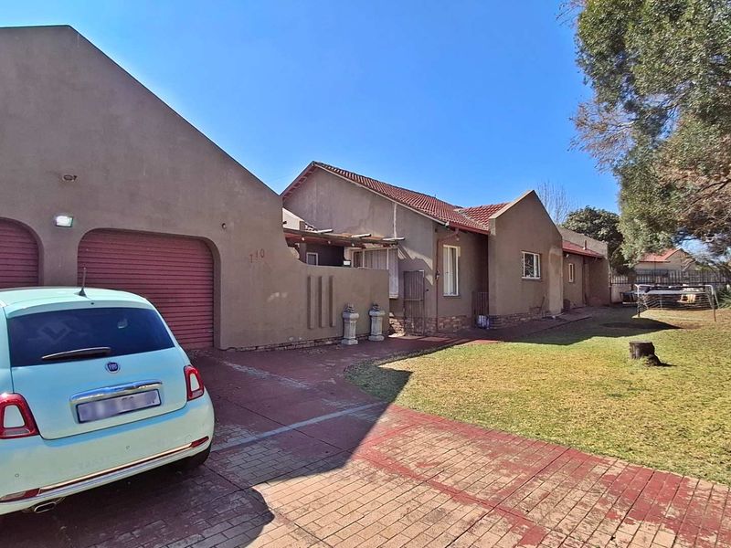 Front view of a residential property featuring a double garage, paved driveway, and a spacious front lawn area.