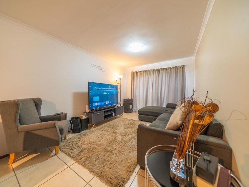 A comfortable living room featuring tiled flooring and neutral wall finishes, providing a functional space for relaxation and entertainment.