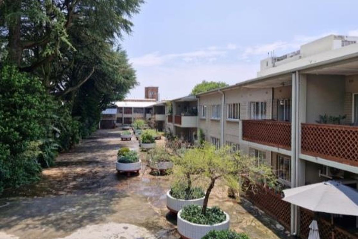 Rear view of the apartment complex featuring a paved courtyard, large planters, and multiple levels of balconies with brick balustrades.