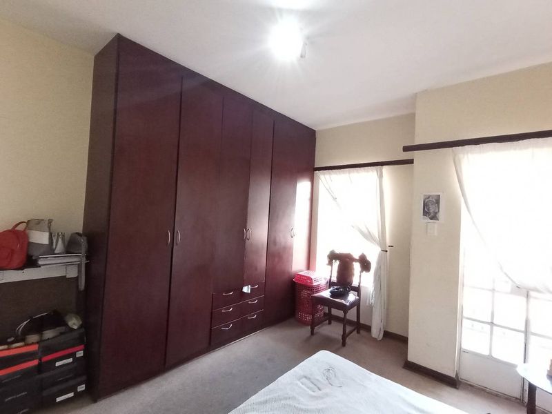 A bedroom featuring dark wood built-in cupboards, carpeted flooring, and access to an outdoor area through french doors.