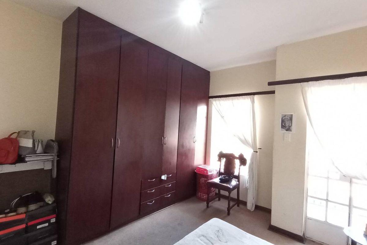 A bedroom featuring dark wood built-in cupboards, carpeted flooring, and access to an outdoor area through french doors.