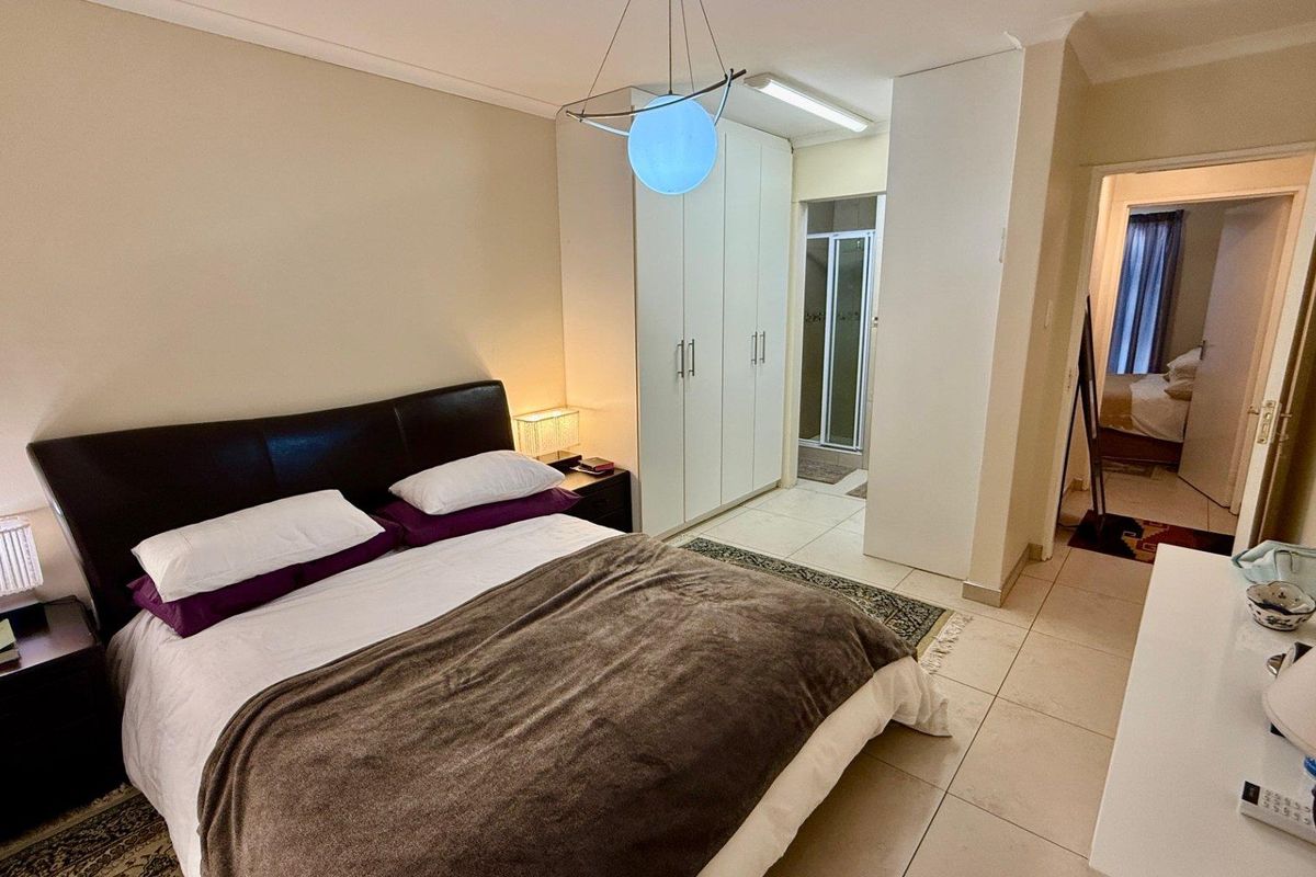 A bedroom featuring built-in cupboards, tiled flooring, and an en-suite bathroom access.