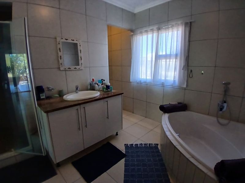 A functional bathroom featuring a vanity cabinet with a countertop basin, a built-in bathtub, and a separate shower enclosure with tiled finishes.