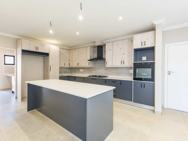Modern kitchen featuring a central island, two-tone cabinetry, built-in oven, gas hob, extractor fan, and neutral tiled flooring.