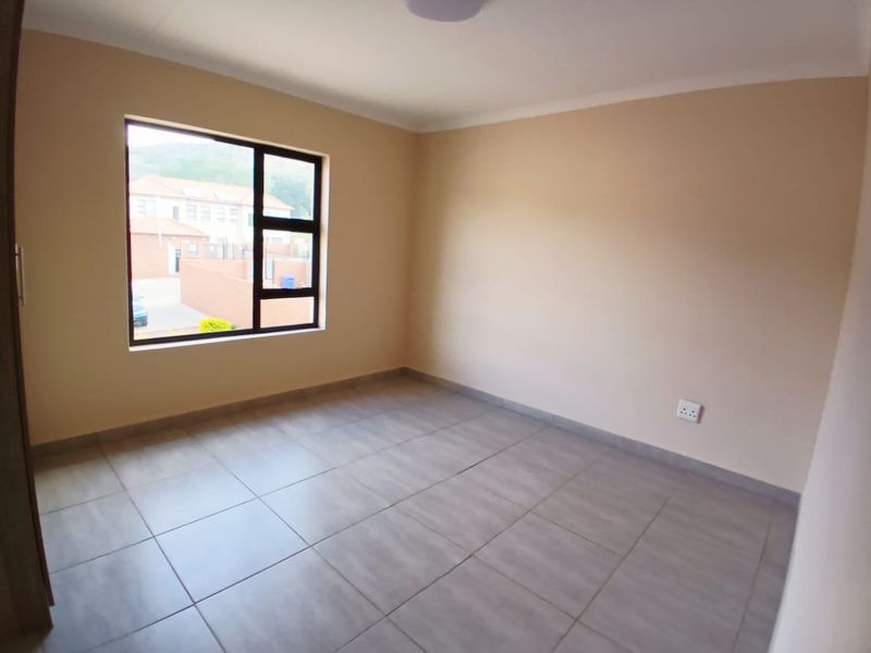 A clean, empty bedroom featuring neutral wall paint, large aluminium-framed windows, and modern tiled flooring, ready for personalization.