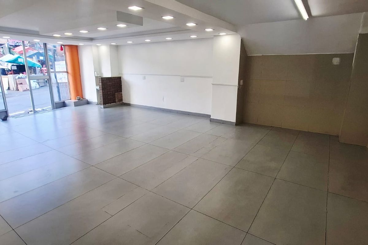 Spacious open-plan commercial unit featuring large glass storefront windows, recessed ceiling lighting, and durable tiled flooring, suitable for various business applications.