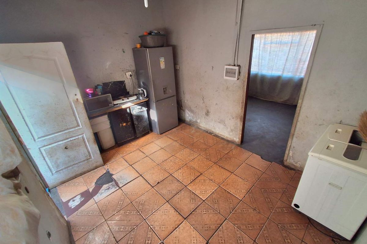 A basic kitchen area featuring tiled flooring and visible wall wear, requiring significant renovation and cosmetic updates to improve functionality and aesthetic appeal.