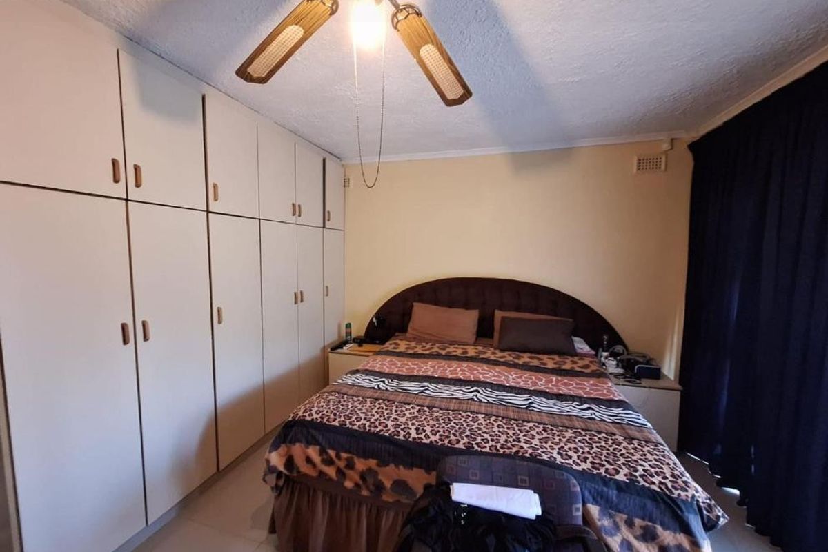 A bedroom featuring extensive built-in cupboards for storage and a ceiling fan, providing a functional and practical living space.