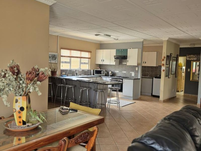 Spacious open-plan living and kitchen area featuring tiled floors, a central kitchen island with breakfast bar, and decorative coffered ceilings.
