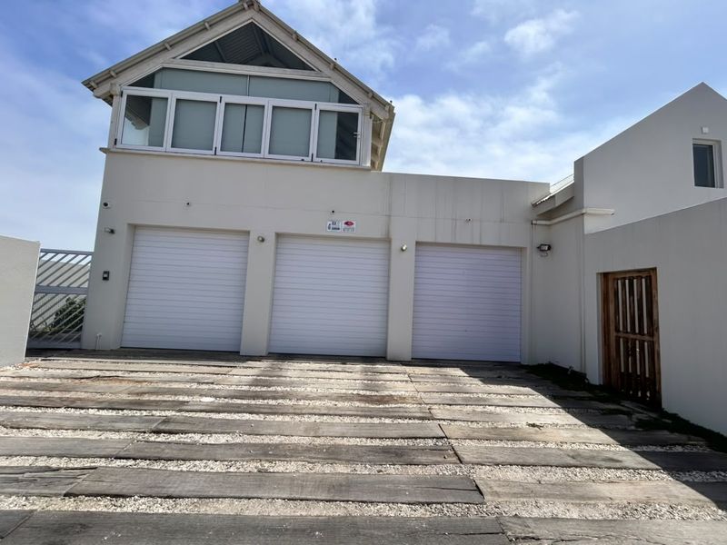 Front elevation featuring a triple garage with roller doors, a timber sleeper driveway, and an upper-level balcony.