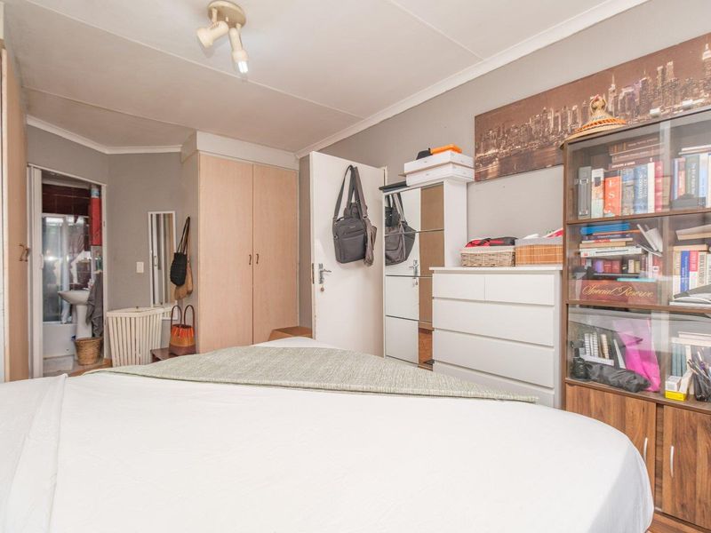 A functional bedroom featuring built-in cupboards and direct access to an en-suite bathroom, offering a practical layout for comfortable living.