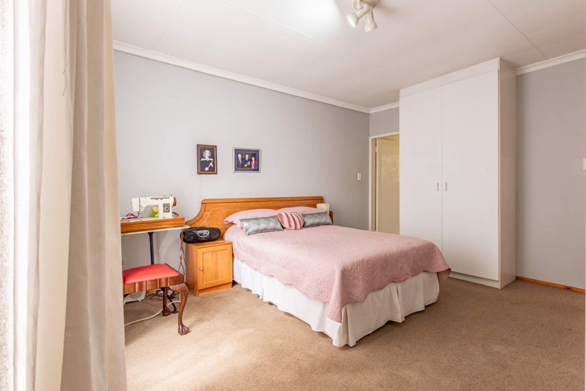 A well-lit bedroom featuring neutral wall tones, fitted carpeting, and a built-in wardrobe providing ample storage space.