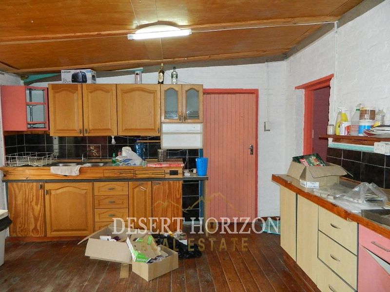 A dated kitchen featuring wooden cabinetry, laminate countertops, and timber flooring, offering significant potential for modernization and renovation.