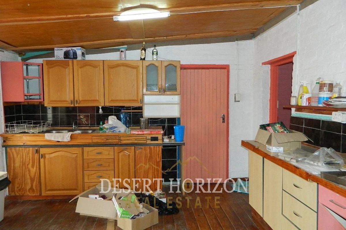 A dated kitchen featuring wooden cabinetry, laminate countertops, and timber flooring, offering significant potential for modernization and renovation.