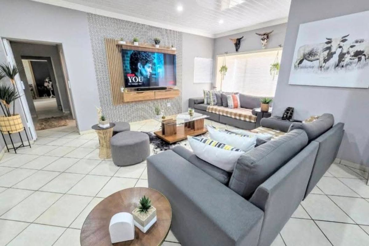 A well-maintained living room featuring tiled flooring, a decorative feature wall with integrated media unit, and recessed ceiling lighting.