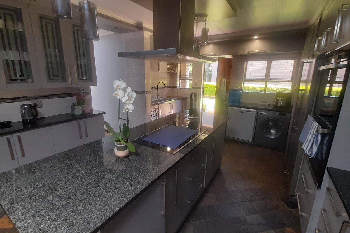 Modern kitchen featuring a central island with a built-in hob, extractor fan, granite countertops, and integrated cabinetry with ample storage space.