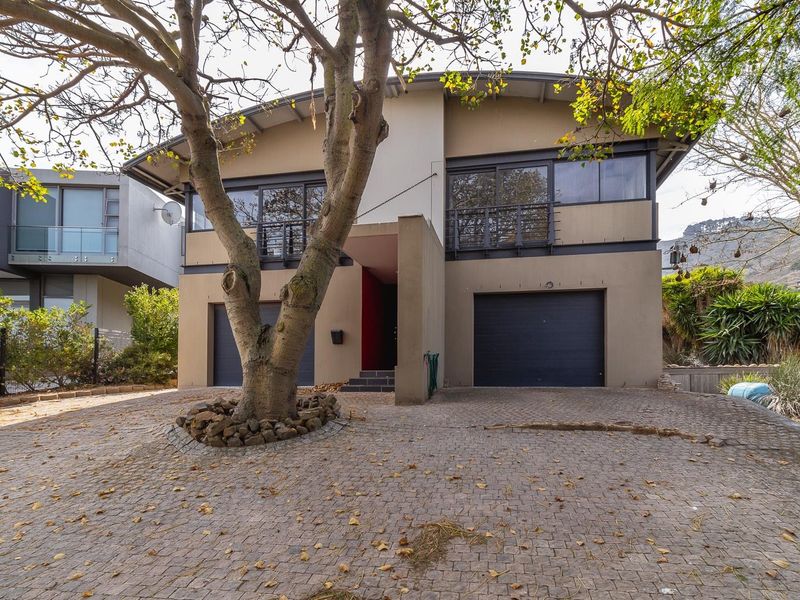 Front elevation of a modern two-story house featuring a double garage, paved driveway, and upper-level balcony.