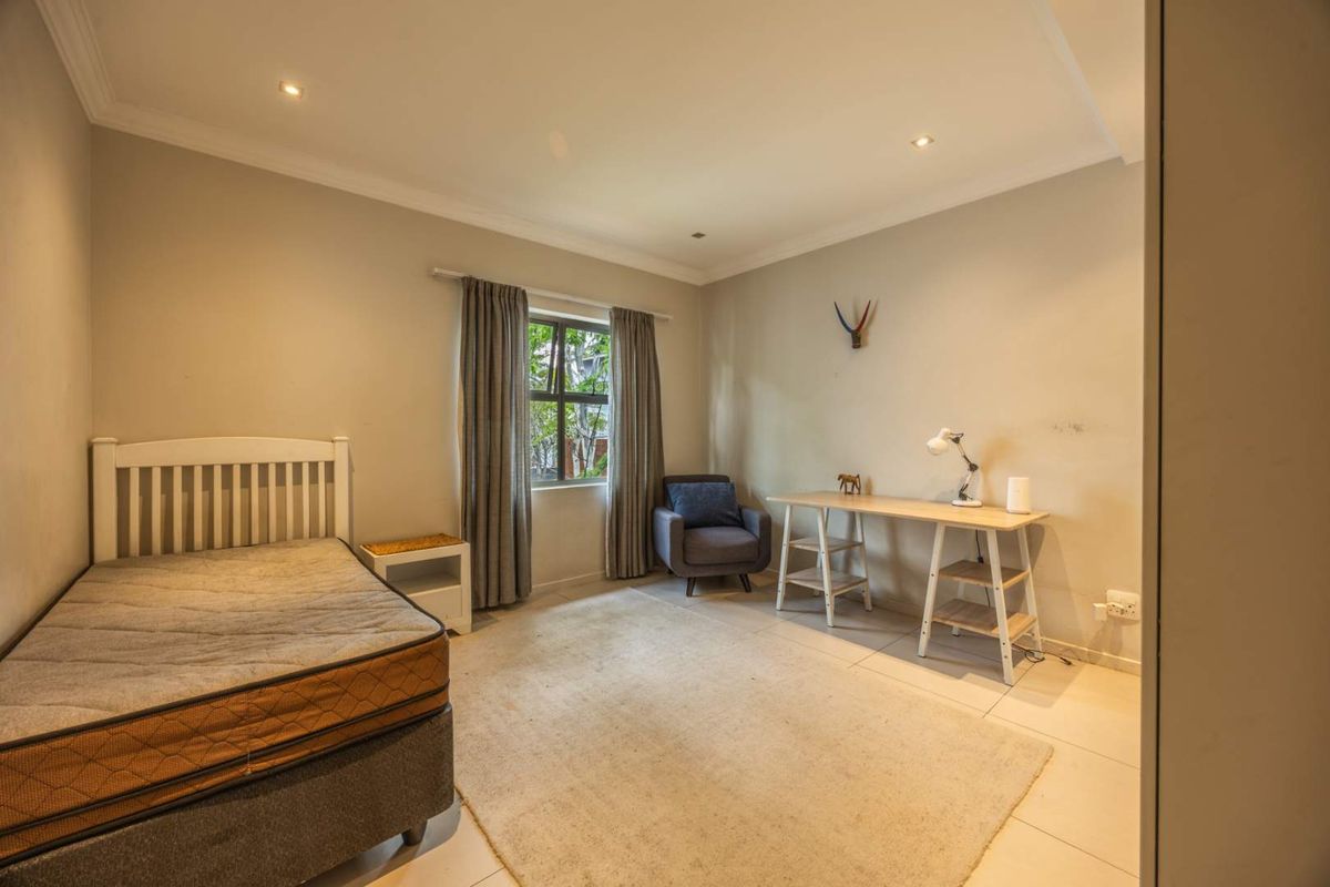 A well-lit bedroom featuring tiled flooring, coved ceilings, and recessed downlights, offering a neutral canvas for personalization.