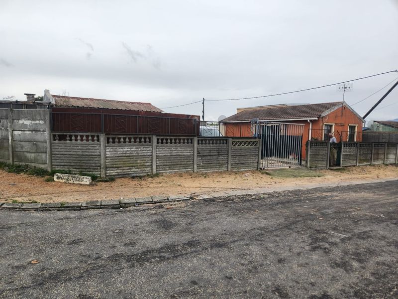 Front view of a residential property featuring a brick facade, tiled roof, and a precast concrete boundary wall with metal security gates.