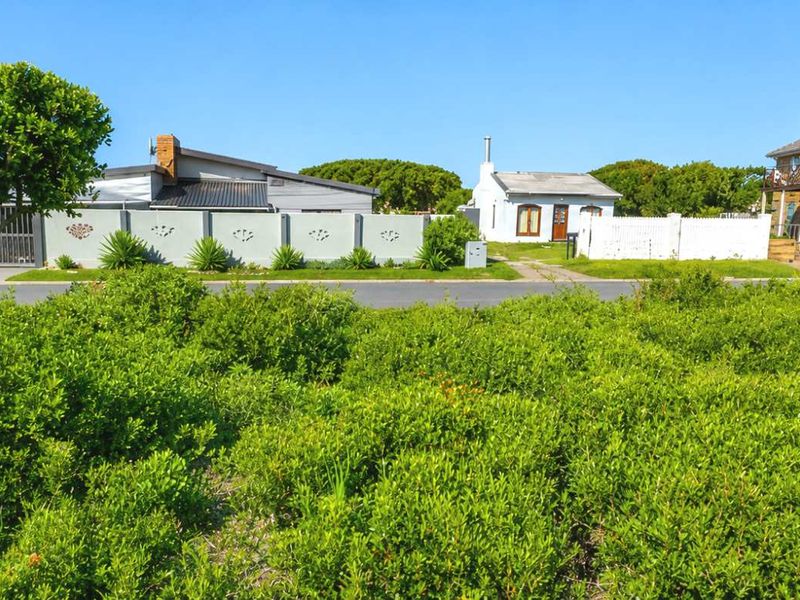 A street-level view of the residential plot featuring established vegetation and surrounding neighborhood properties.