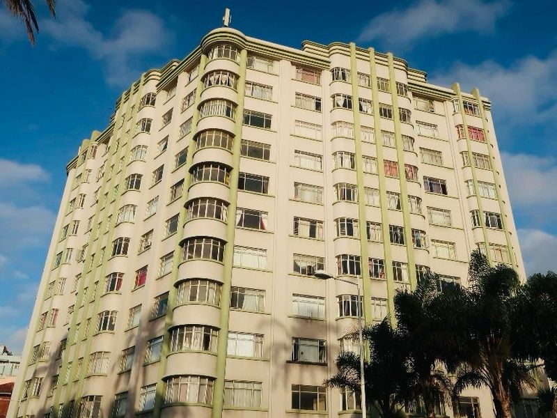 A multi-story apartment building featuring distinctive curved architectural corners and a classic facade with numerous casement windows.