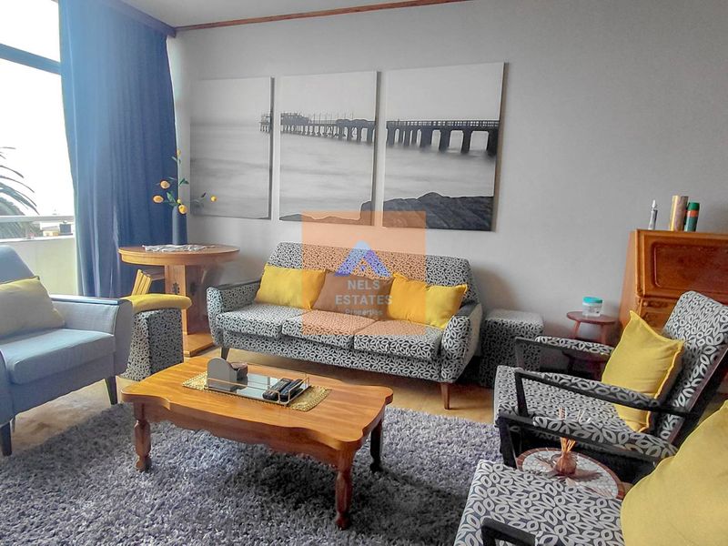 A comfortable living room featuring tiled flooring and a large sliding glass door providing access to the outdoor area.