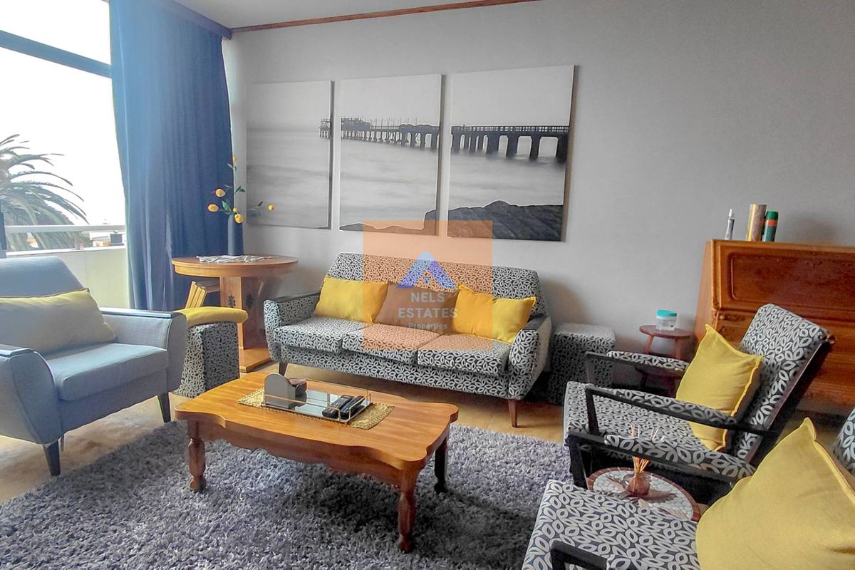 A comfortable living room featuring tiled flooring and a large sliding glass door providing access to the outdoor area.