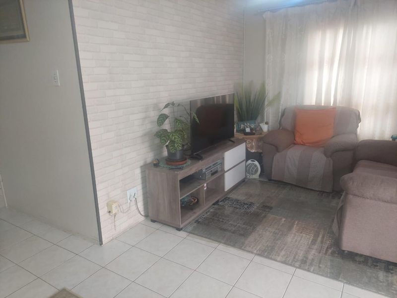 A living room area featuring tiled flooring and a brick-effect feature wall, providing a neutral base for interior updates.