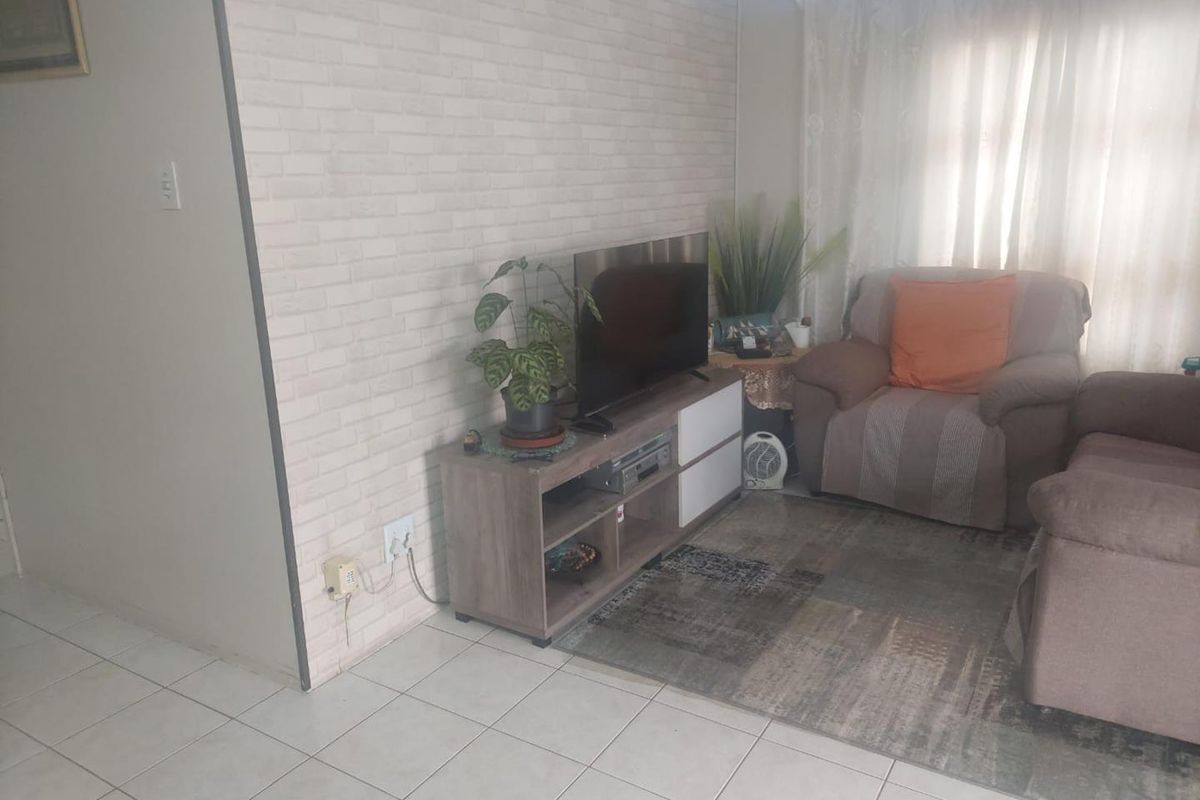 A living room area featuring tiled flooring and a brick-effect feature wall, providing a neutral base for interior updates.