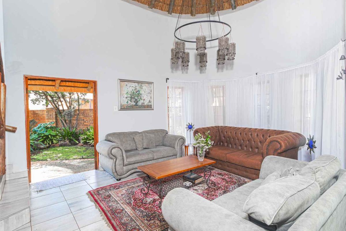 Spacious living area featuring a high thatched ceiling, tiled flooring, and direct access to the garden through a doorway.