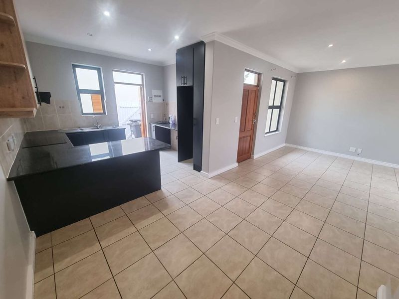 Spacious open-plan living area featuring a modern kitchen with granite countertops, ample cabinetry, and tiled flooring throughout.