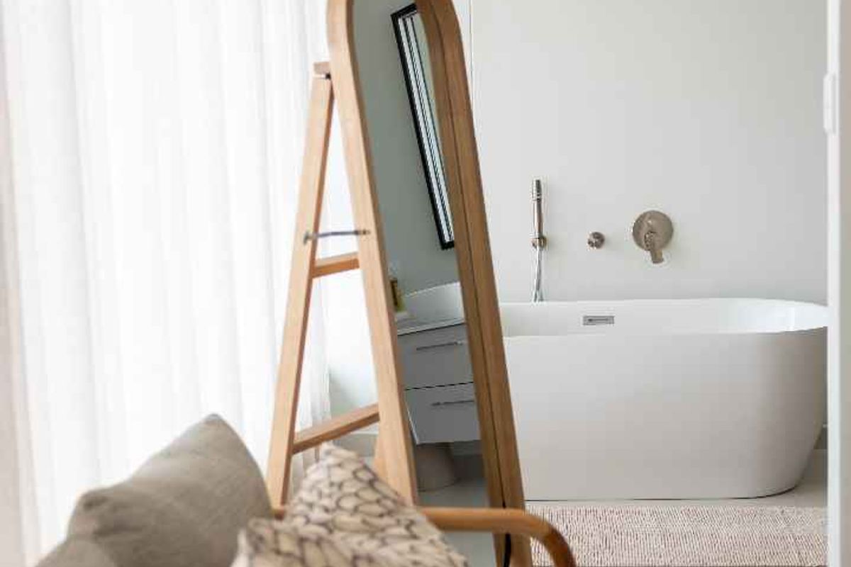 A modern bathroom featuring a sleek freestanding bathtub with wall-mounted fixtures and neutral tiled flooring, offering a clean and contemporary aesthetic.