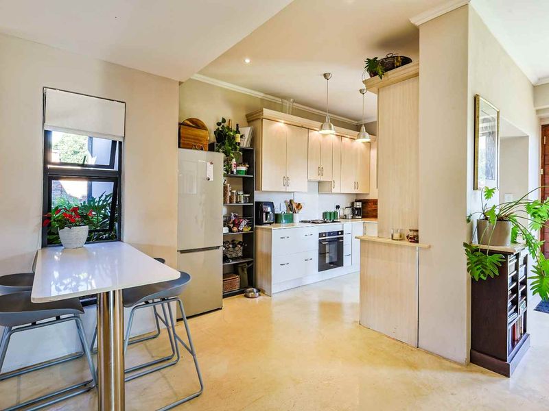 A functional kitchen featuring light-toned cabinetry, integrated appliances, and polished concrete flooring, seamlessly connected to the home's entrance area.