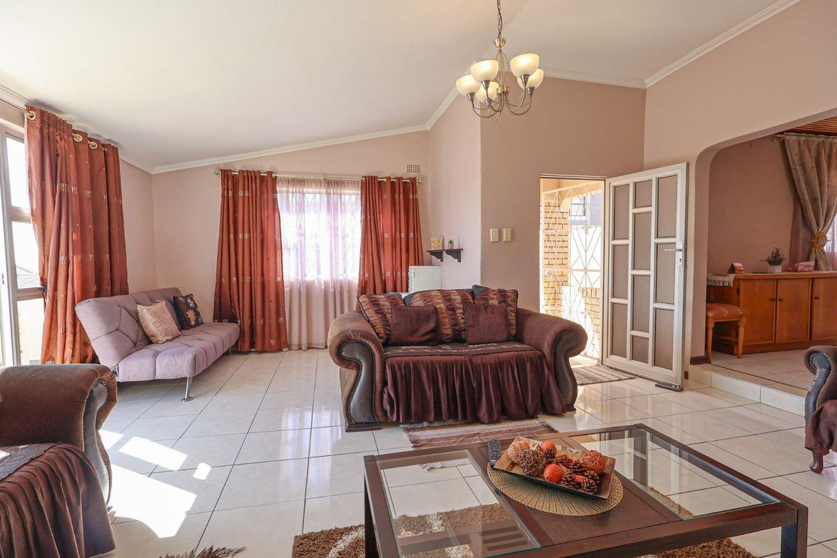 Spacious living room featuring tiled flooring, a vaulted ceiling, and a glass-paneled door leading to an adjacent area.