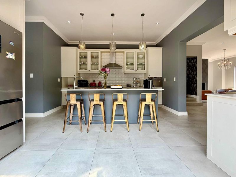 Modern kitchen featuring a central island, sleek cabinetry, subway tile backsplash, and contemporary pendant lighting, creating a bright and functional culinary space.