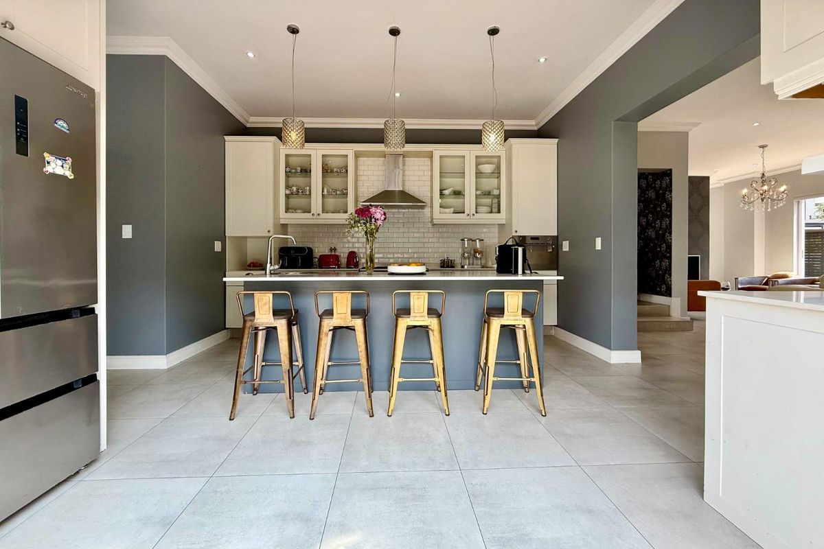 Modern kitchen featuring a central island, sleek cabinetry, subway tile backsplash, and contemporary pendant lighting, creating a bright and functional culinary space.