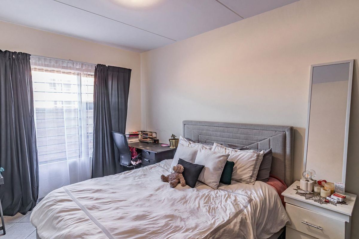A functional bedroom featuring tiled flooring and security bars on the window, providing a comfortable and secure living space.
