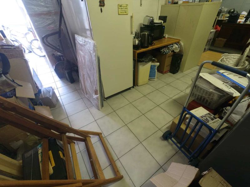 A utility or storage area featuring tiled flooring, currently utilized for general storage and workspace organization.