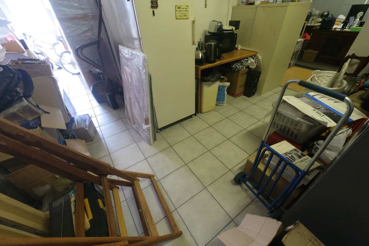 A utility or storage area featuring tiled flooring, currently utilized for general storage and workspace organization.