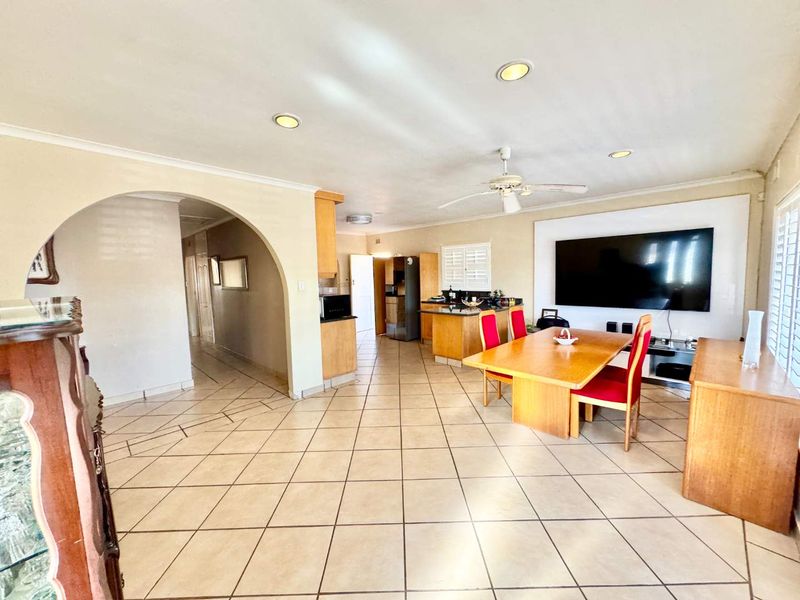 Spacious open-plan living and dining area featuring tiled flooring, recessed lighting, and a functional kitchen layout with built-in cabinetry.