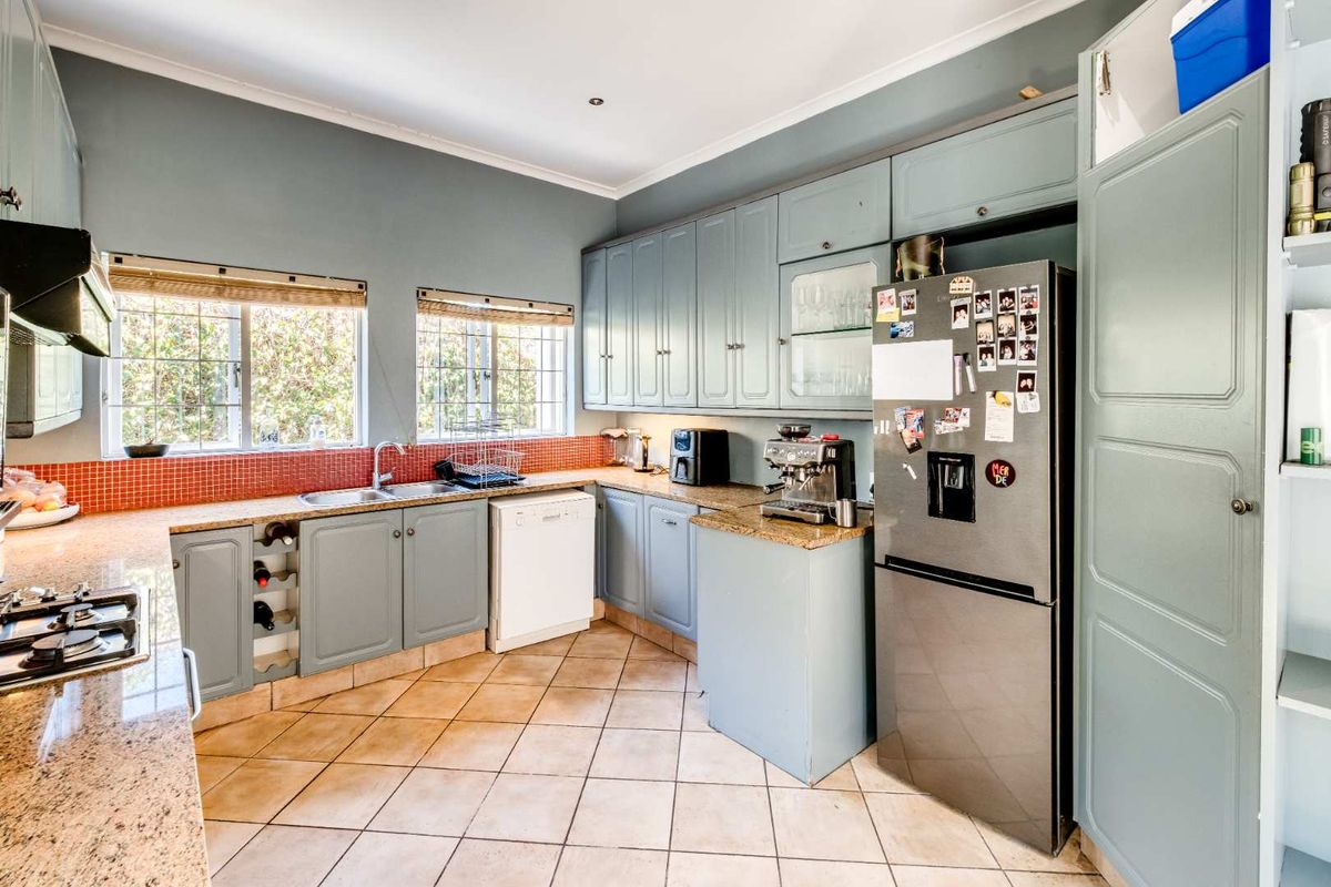 A functional kitchen featuring light blue cabinetry, granite countertops, a tiled backsplash, and integrated cooking appliances.