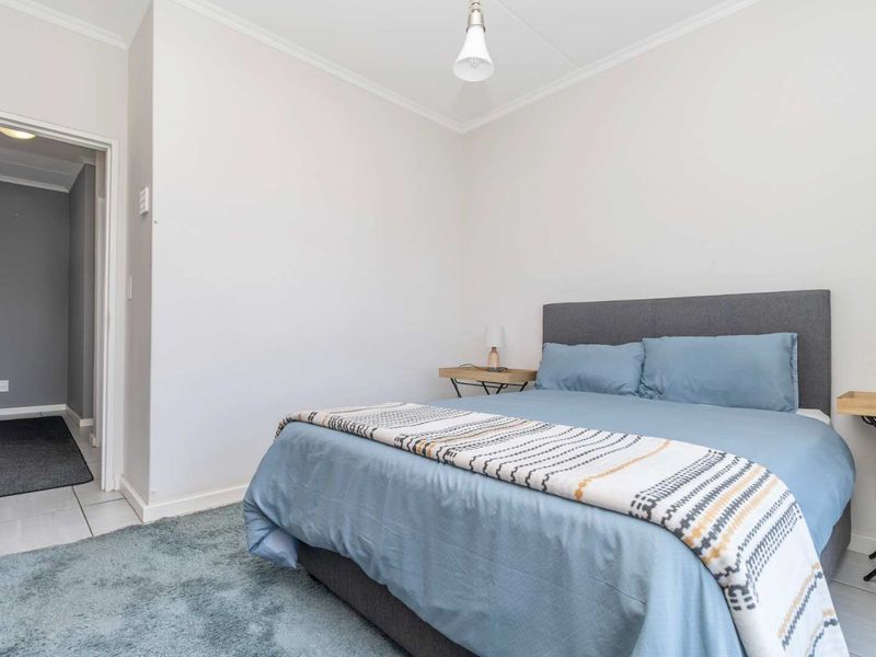 A well-maintained bedroom featuring neutral walls, tiled flooring, and a simple pendant light fixture, offering a clean and functional living space.