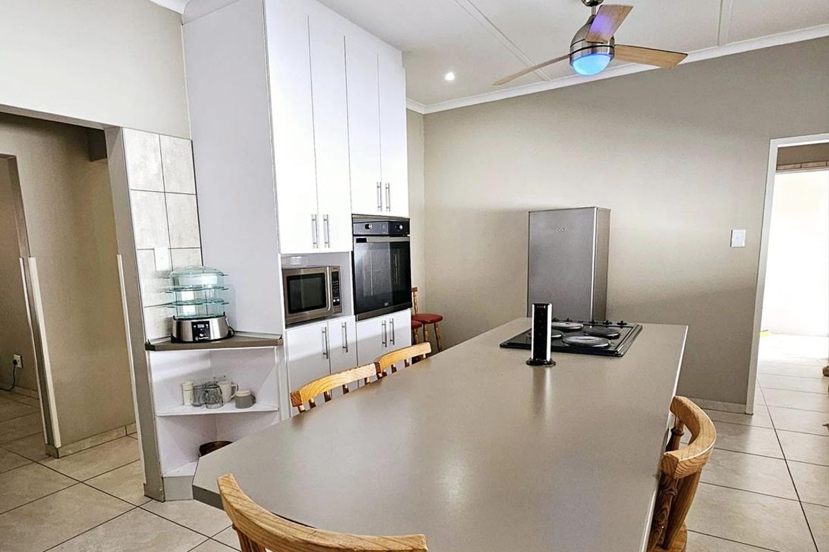 Modern kitchen featuring a central island with a built-in cooktop, white cabinetry, integrated oven, and tiled flooring.