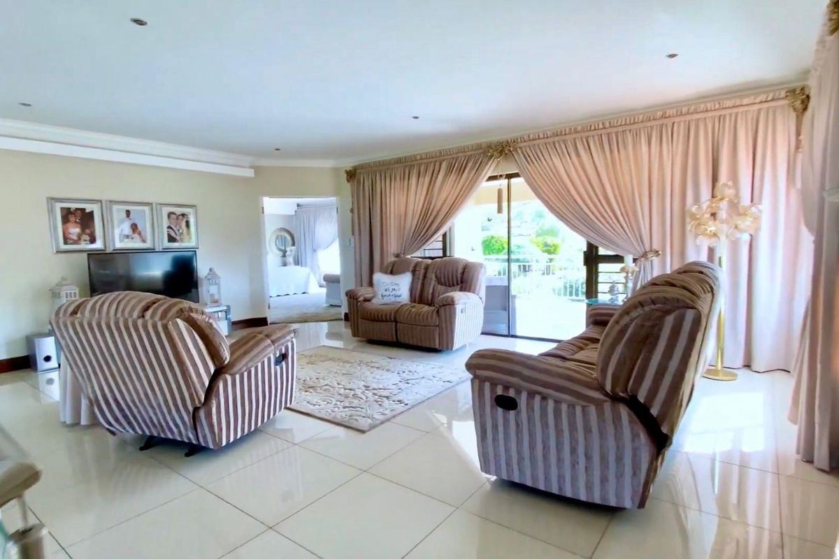Spacious living room featuring polished floor tiles, recessed downlighting, and large sliding glass doors providing access to the outdoor patio area.