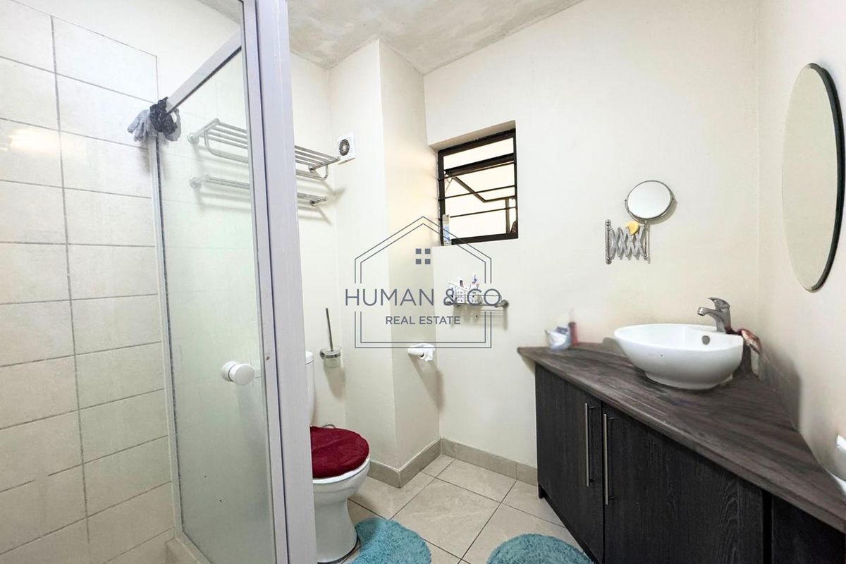 A functional bathroom featuring a glass-enclosed shower, a vanity cabinet with a vessel sink, and tiled flooring.