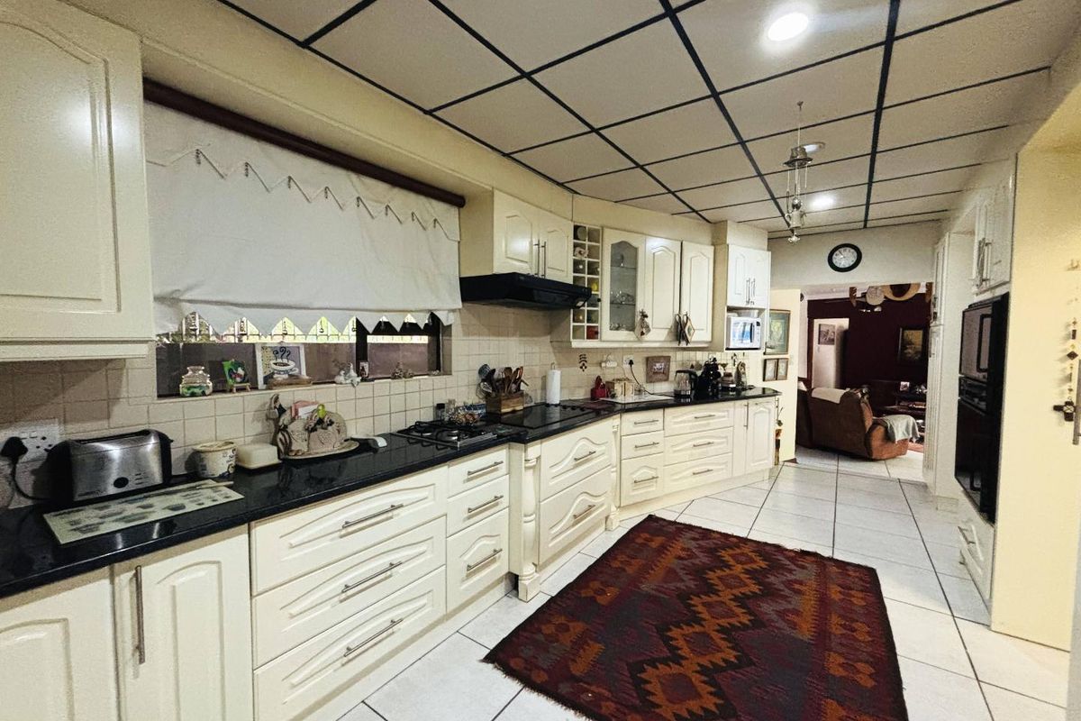 Spacious kitchen featuring cream cabinetry, granite countertops, built-in appliances, and tiled flooring, offering a functional layout with potential for modern updates.