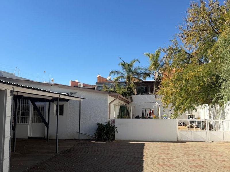 A paved rear courtyard area featuring a covered patio space, secure boundary walls, and gated access.