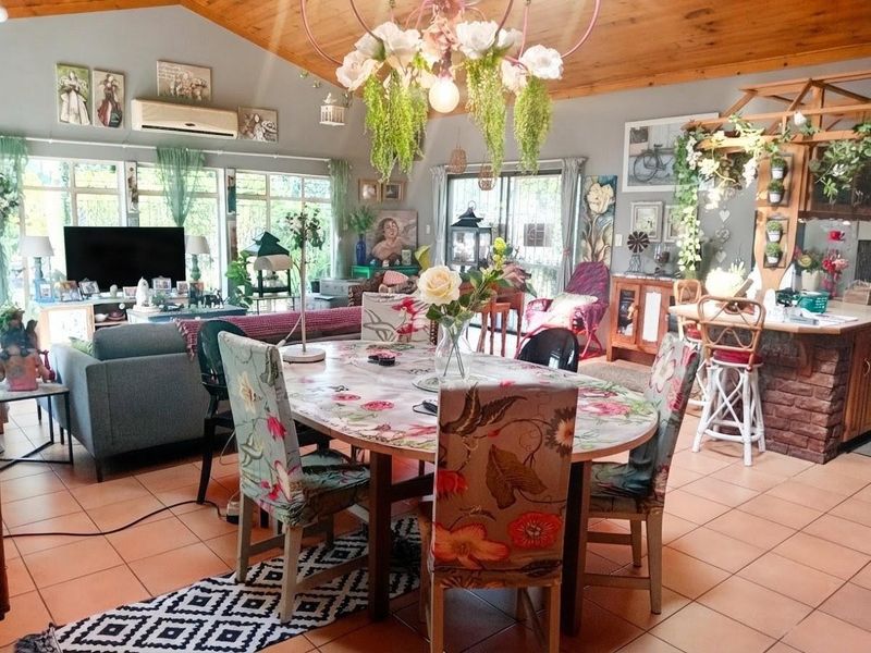Spacious open-plan living and dining area featuring exposed timber ceilings, ceramic tiled flooring, and a kitchen island with a brick base.