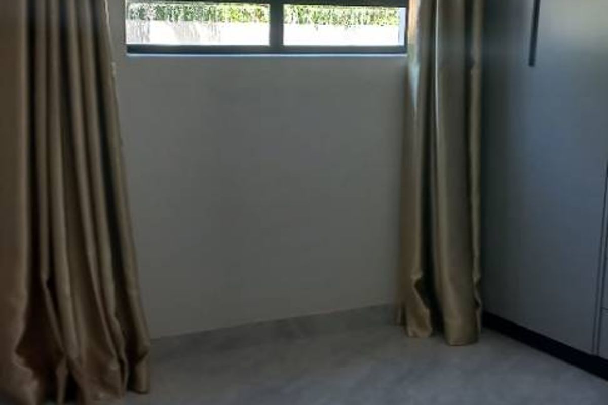 A bright bedroom featuring modern tiled flooring, built-in cabinetry, and large windows that allow for ample natural light.